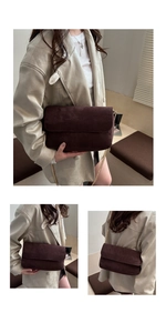 Detail view of dark brown suede crossbody bag with elegant gold chain strap and flap cover