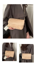Detail of minimalist beige suede crossbody bag with elegant gold metal chain strap
