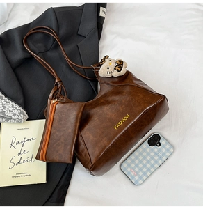 Detail of vintage brown oil wax leather tote bag with a mini coin purse and cat charm