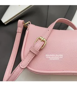 Close-up of pink pebbled leather shoulder bag with adjustable strap and gold buckle