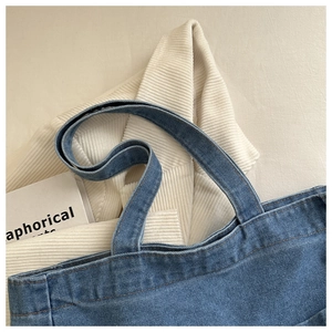 Close-up of blue denim tote bag showing washed fabric texture and double stitching detail