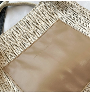 Vue détaillée de la texture de paille tissée et du patch en cuir gaufré sur le sac