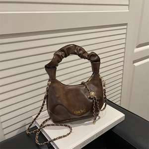 Deep brown crescent dumpling bag with pleated handle and gold chain strap in minimalist style