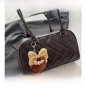Dettaglio della borsa trapuntata marrone scuro con ciondolo di peluche e doppi manici sottili