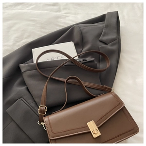 Detail of vintage brown shoulder bag with golden buckle and stitching on a grey blazer