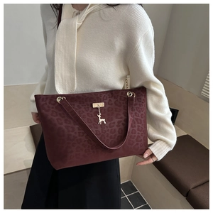 Dettaglio borsa shopper leopardata bordeaux con ciondolo cervo dorato e texture in pelle