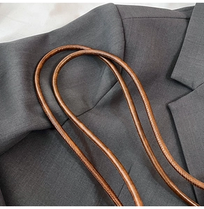 Macro detail of brown pebbled leather shoulder strap with premium hand-stitched seams