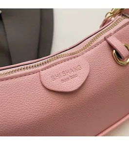 Close-up of pink lychee grain leather handbag with gold zipper and embossed branding