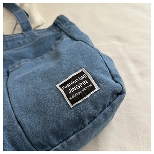 Close-up of light blue denim tote bag texture with fashion text patch embroidery