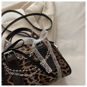 Detail view of leopard print bag with silver chains, crosses and white lace bows