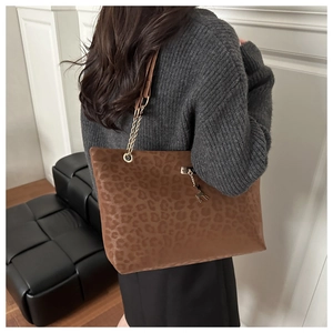 Dettaglio borsa tote leopardata con tracolla a catena dorata e ciondolo a forma di cervo