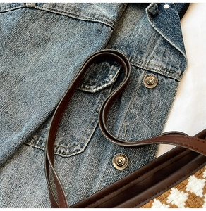 Close-up of woven tote bag texture with brown leather strap and denim background