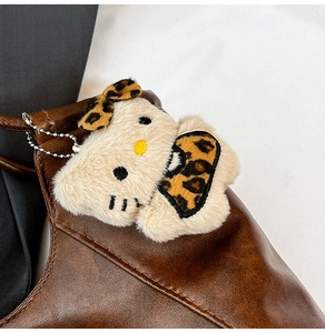 Close-up of Hello Kitty plush keychain with leopard print bow on brown tote bag