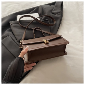 Detail of vintage brown leather bag with golden twist lock and long shoulder strap