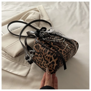 Detail of leopard print shoulder bag featuring lace bow and metallic cross charms