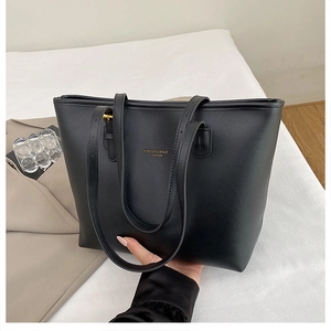 Detailed view of the gold logo lettering and textured leather surface on this black tote bag