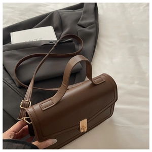Detail of premium brown faux leather handbag with gold twist lock and wide handle