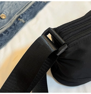 Dettaglio della borsa a tracolla in nylon nero con cerniere multistrato e cinturino