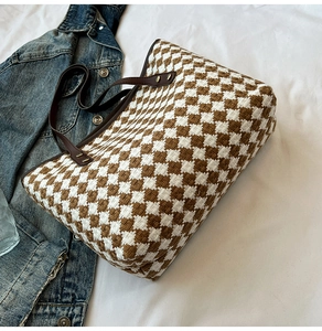 Close-up of brown and white checkered woven tote bag texture with leather handle
