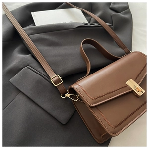 Detail of a brown PU leather bag featuring a gold metal lock and reinforced stitching
