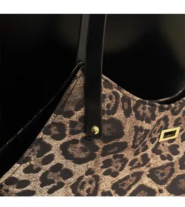 Detail of leopard print tote bag with golden hardware and black leather handle straps