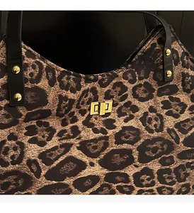 Close-up of leopard print canvas bag featuring a golden twist lock and rivet hardware