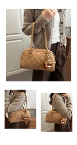 Dettaglio della borsa bowling trapuntata beige con doppi manici e ciondolo di peluche