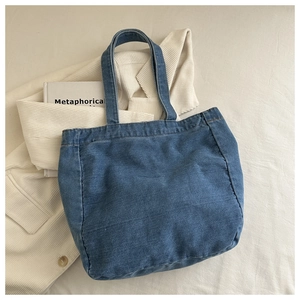 Detail of blue denim tote bag with stitching on fabric, styled with a book for a casual look