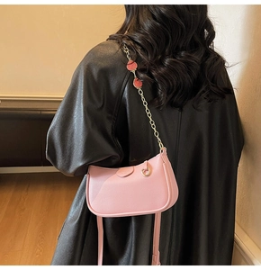 Detail of pink lychee leather handbag with strawberry pendants and metal chain