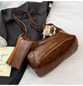 Detail of dark brown tote bag with fashion lettering, small pouch and plush charm
