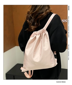 Detail view of pink drawstring backpack featuring smooth nylon texture and wide straps