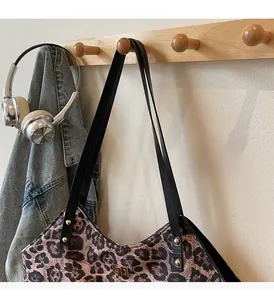 Leopard print tote bag hanging on hook with headphones and denim jacket scene