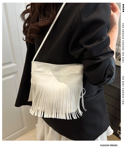 Detailed view of white fringe shoulder bag with long tassels and thin strap on a model