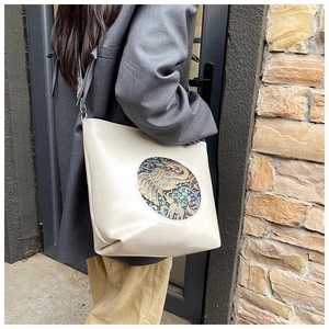 Close-up of beige vintage tote bag featuring an ethnic elephant embroidery and floral patch