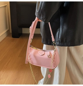 Detail of pink leather underarm bag with golden strawberry chain and adjustable strap