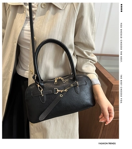 Detailed view of black retro shell bag with gold hardware and textured faux leather