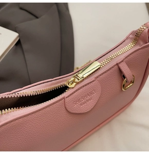 Macro shot of pink lychee leather bag with gold zipper and embossed brand logo detail