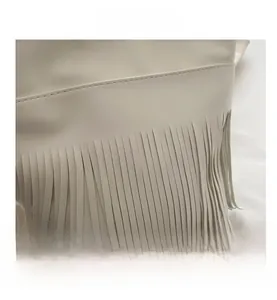 Close-up of white fringe tassels and stitching details on a vintage shoulder bag