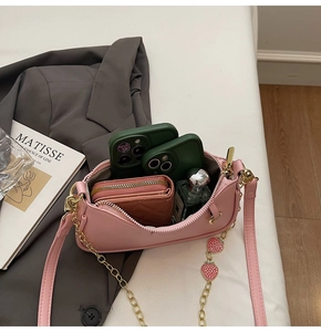 Pink litchi grain leather bag interior with gold chain strap and strawberry charm detail
