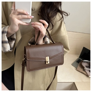 Detail of vintage brown leather handbag with gold clasp and adjustable strap