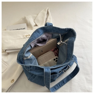 Detail view of denim tote bag interior showing capacity with phone and wallet inside