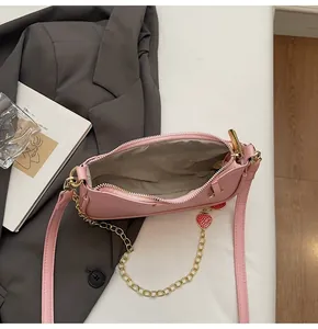 Pink pebbled leather baguette bag featuring strawberry charms and gold hardware detail