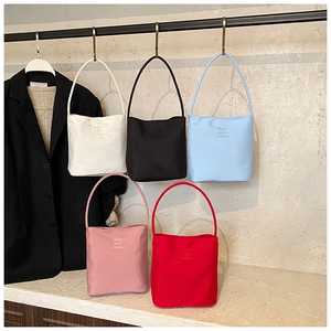 Détail de la broderie 'Hope and future' sur cinq sacs à main en nylon colorés
