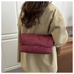 Close-up of burgundy faux suede shoulder bag with elegant gold chain strap detail