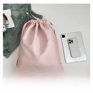Pink drawstring leather backpack shown with iPad and accessories for size reference