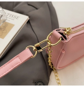 Detail of pink lychee grain leather handbag featuring gold hardware and chain strap