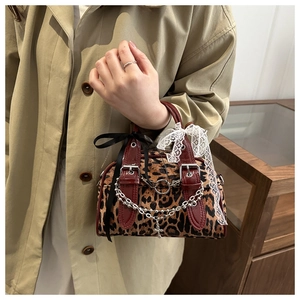 Detail of leopard print bag featuring black bow, white lace, and silver cross charm