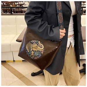 Detail of vintage brown leather tote bag with elephant relief and colorful woven strap