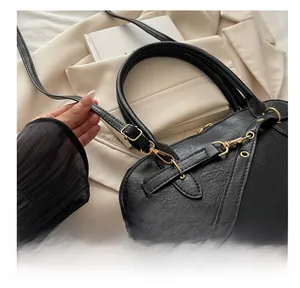Close-up of black litchi pattern PU leather handbag with golden metal adjustable buckle