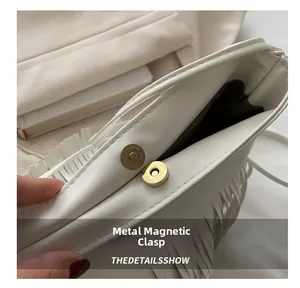 Detailed macro shot of the magnetic metal clasp on the beige tassel handbag